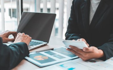 Şirketin gelir grafiğiyle ilgili iş adamları, yöneticiler ve muhasebecilerden oluşan bir ekiple ofiste dizüstü bilgisayarlar, hesap makineleri ve finans konseptiyle bir araya gelmek.