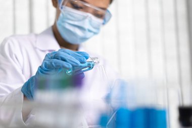 Bilim insanları kimyasal bileşimin ve biyolojik kütlesinin bilimsel bir laboratuvarda, bilim adamlarında ve laboratuar konseptinde tespit edilmesine hazırlanmak için mavi kimyasal test tüpleri taşıyorlar..