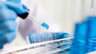 Bilim insanları kimyasal bileşimin ve biyolojik kütlesinin bilimsel bir laboratuvarda, bilim adamlarında ve laboratuar konseptinde tespit edilmesine hazırlanmak için mavi kimyasal test tüpleri taşıyorlar..