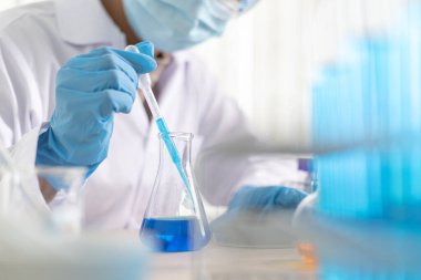 Bilim insanları kimyasal bileşimin ve biyolojik kütlesinin bilimsel bir laboratuvarda, bilim adamlarında ve laboratuar konseptinde tespit edilmesine hazırlanmak için mavi kimyasal test tüpleri taşıyorlar..