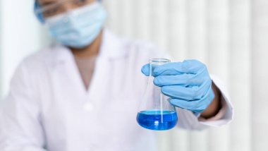 Bilim insanları kimyasal bileşimin ve biyolojik kütlesinin bilimsel bir laboratuvarda, bilim adamlarında ve laboratuar konseptinde tespit edilmesine hazırlanmak için mavi kimyasal test tüpleri taşıyorlar..