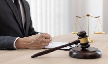 Yargıç ya da avukat mahkeme salonunda belgeler üzerinde çalışır ve adalet, doğruluk, dava ve adalet kavramları için çeşitli yasaları analiz eder..