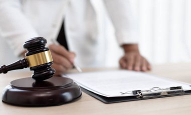 Yargıç ya da avukat mahkeme salonunda belgeler üzerinde çalışır ve adalet, doğruluk, dava ve adalet kavramları için çeşitli yasaları analiz eder..