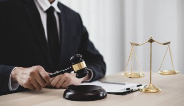 Yargıç ya da avukat mahkeme salonunda belgeler üzerinde çalışır ve adalet, doğruluk, dava ve adalet kavramları için çeşitli yasaları analiz eder..