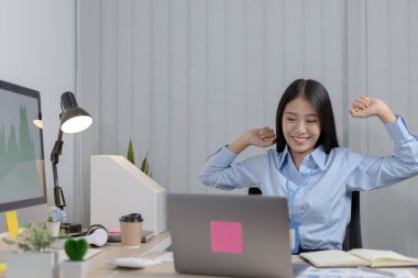 Asyalı iş kadını fazla mesai yaptıktan sonra dinleniyor. Mesai bittikten sonra işte dinlenen mutlu kadınlar..