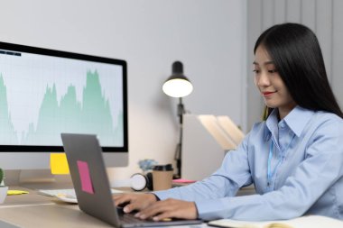 Asyalı kadın internet üzerinden neşeli bir gülümsemeyle çalışıyor, evde kalıyor, Yeni Normal, Covid-19 Coronavirus, Sosyal Mesafe, İnternet Öğrenimi.