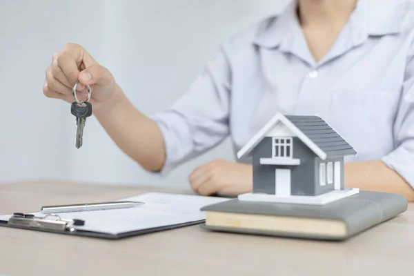 Real estate agent holds the keys to send to the client and offers the conditions for signing the house sale agreement and home insurance to the client, Home sales and home insurance concept.