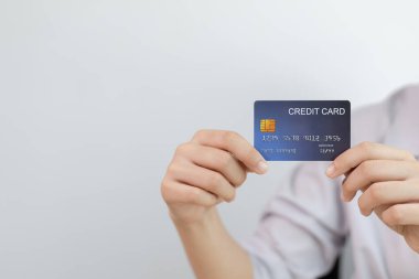 Genç Asyalı kadın çalışanın elinde mavi bir kredi kartı, online alışveriş ve online bankacılık kavramı var..