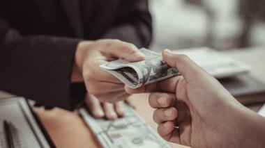 İşadamları, yasadışı arazi ve gayrimenkul, iş dolandırıcılığı ve sosyal adaletsizlik, yolsuzluk ve rüşvet kavramını satın almak için sözleşmeler imzalayan çalışanlara dolar dağıtıyor.