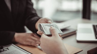 İşadamları, yasadışı arazi ve gayrimenkul, iş dolandırıcılığı ve sosyal adaletsizlik, yolsuzluk ve rüşvet kavramını satın almak için sözleşmeler imzalayan çalışanlara dolar dağıtıyor.