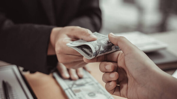 Businessmen give dollars to bribe employees in signing contracts to buy illegal land and real estate, Business fraud and social injustice, corruption and bribery concept.