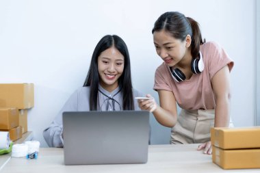 İki genç Asyalı kadın internet üzerinden alışveriş yapan müşterilere gülümseyerek sohbet ediyor ve anlaşmanın imzalanma emrini onaylıyorlar. İnternetten ürün satmak ya da ev konseptinde serbest iş yapmak..