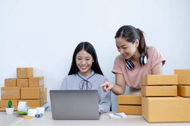 İki genç Asyalı kadın internet üzerinden alışveriş yapan müşterilere gülümseyerek sohbet ediyor ve anlaşmanın imzalanma emrini onaylıyorlar. İnternetten ürün satmak ya da ev konseptinde serbest iş yapmak..