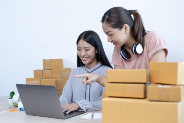 İki genç Asyalı kadın internet üzerinden alışveriş yapan müşterilere gülümseyerek sohbet ediyor ve anlaşmanın imzalanma emrini onaylıyorlar. İnternetten ürün satmak ya da ev konseptinde serbest iş yapmak..