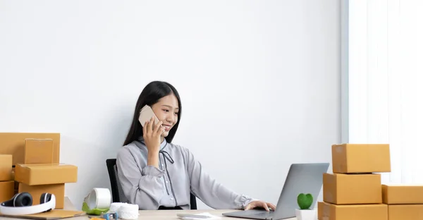 Young Asian women are selling products online and are using mobile phones to chat with customers to confirm orders, Selling products online or doing freelance work at home concept.