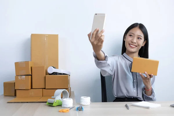 Business women selling online are taking pictures of themselves and their merchandise as a confirmation of delivery to customers, Selling products online or doing freelance work at home concept.
