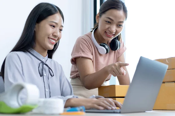 Two young Asian women chat with bright smiles to customers who shop online via laptop and confirm the order to close the deal, Selling products online or doing freelance work at home concept.