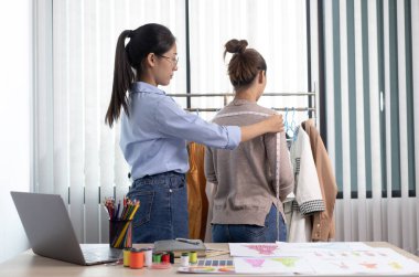 Asyalı giyim tasarımcıları müşterilerin beden ölçülerini tasarım odalarında terzilik için ölçüyor, yeni bir kıyafet koleksiyonu yaratıyor, tasarımcının çalışmalarını yaratıyor..