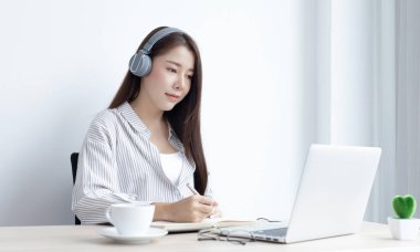 Asyalı kadın evinde dizüstü bilgisayarıyla çalışıyor, evde kalıyor, Yeni Normal, Covid-19 Coronavirus, Sosyal Mesafe, İnternet Öğrenimi.