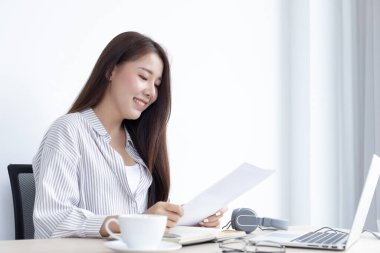 Asyalı kadın evinde dizüstü bilgisayarıyla çalışıyor, evde kalıyor, Yeni Normal, Covid-19 Coronavirus, Sosyal Mesafe, İnternet Öğrenimi.