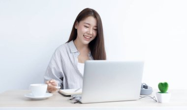 Asyalı kadın evinde dizüstü bilgisayarıyla çalışıyor, evde kalıyor, Yeni Normal, Covid-19 Coronavirus, Sosyal Mesafe, İnternet Öğrenimi.