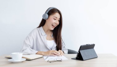 Asyalı bir kadın dizüstü bilgisayarda görüntülü sohbet yapıyor ve sosyal uzaklıklarda internet sohbetinden hoşlanıyor. Online iletişim, evde kalmak, Covid-19 koronavirüsü, sosyal mesafe, internet öğrenimi..