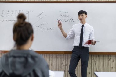 Matematik ya da beden öğretmeni, yeni dönem öğrencilerinin, öğrenci eğitiminin ve mutlu öğretim konseptinin açılışı için sınıfta lise öğrencilerine ders vermeye çalışıyor.