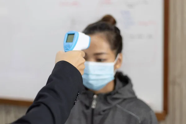 Teacher is taking a student\'s or college student\'s body temperature to measure the body of someone with a high fever and avoid the spread of the new flu, Welcome to the new student semester concept.