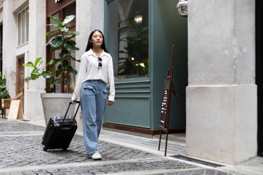 Tatilde seyahat etmek için siyah bavul taşıyan Asyalı kadın, Trolley çanta, uzun haftasonu seyahati, geziyi seviyorum, turizm festivali konseptini seviyorum.