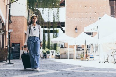 Tatilde seyahat etmek için siyah bavul taşıyan Asyalı kadın, Trolley çanta, uzun haftasonu seyahati, geziyi seviyorum, turizm festivali konseptini seviyorum.