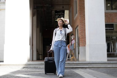 Tatilde seyahat etmek için siyah bavul taşıyan Asyalı kadın, Trolley çanta, uzun haftasonu seyahati, geziyi seviyorum, turizm festivali konseptini seviyorum.