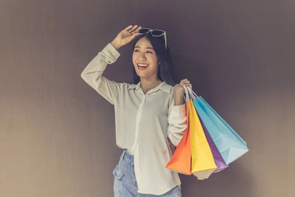 Text input box, Brown background, Young women carrying colorful shopping bags, Happy to buy products concept.