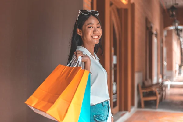 若いアジアの女性が喜んでショッピングバッグを運ぶ店にモールやショッピングセンター 販売日 幸せなショッピングコンセプト — ストック写真