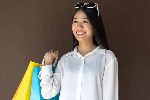 Text input box, Brown background, Young women carrying colorful shopping bags, Happy to buy products concept.