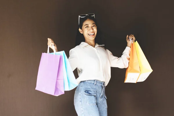 Text input box, Brown background, Young women carrying colorful shopping bags, Happy to buy products concept.