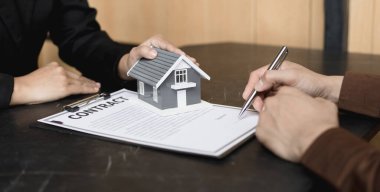 Emlakçı ya da satış müdürü, ev satın alma anlaşmalarını sigorta ile imzalayan müşterilere satın alma sözleşmesini imzalama şartlarını ve şartlarını önerdi..