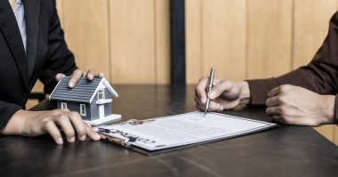 Emlakçı ya da satış müdürü, ev satın alma anlaşmalarını sigorta ile imzalayan müşterilere satın alma sözleşmesini imzalama şartlarını ve şartlarını önerdi..