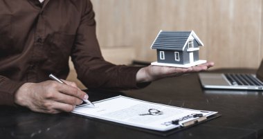 Satış müdürü ya da emlakçı evin anahtarlarını ve sigortalarını müşteriye, emlak hizmetlerine ve sigorta konseptine vermeye hazırlanır..