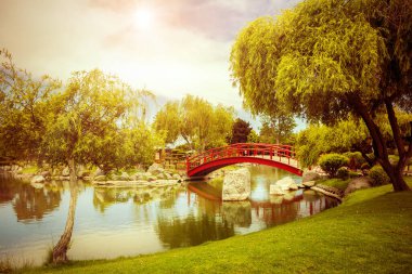 Şili, La Serena 'da gün batımında Japon bahçesinde gölün altında güzel kırmızı bir köprü.