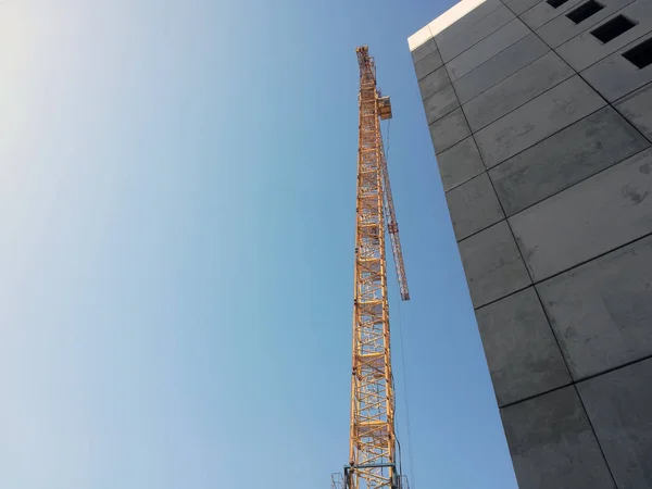 Construction crane rises above the building. Bottom up view on b
