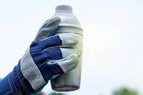 hand in glove holding a jar of liquid nitrogen