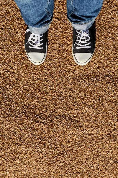 Kum arka plan üzerinde siyah ve beyaz spor ayakkabı