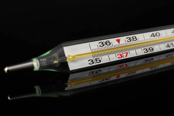 Tıbbi termometre siyah ayna yüzeyine yakın.