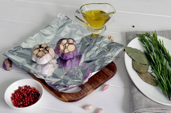 Sarımsak tuz, baharat ve zeytinyağı ile folyo içinde pişirilir. Sarımsakları zeytinyağında biberiye sprigs ile folyo içinde kavurma, ahşap arka plan üzerinde