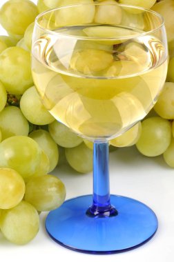 Bir kadeh beyaz şarap ve bir demet üzüm yakın