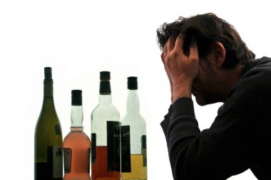 Alkol şişeleri önünde başını tutarak Alkolik