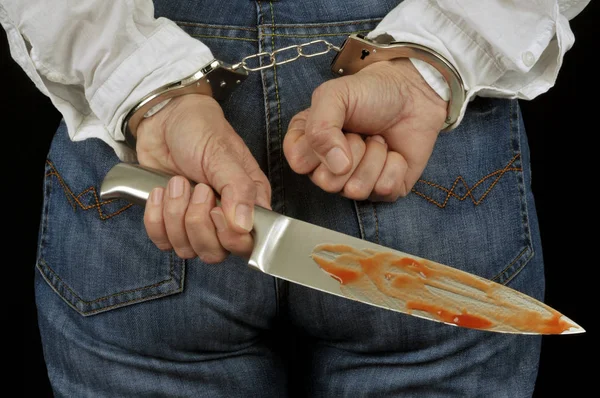 Handcuffed woman from back holding a bloody knife