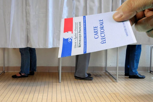 French voter card held in front of polling booths