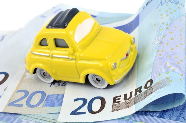 Car budget concept with a car on a wad of euro banknotes close up