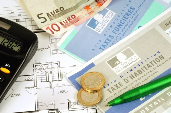 French tax forms and property taxes in grs plan with money, a calculator and a pen on it